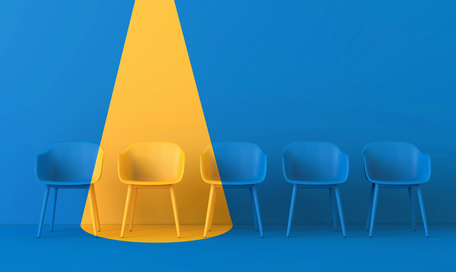 Bild von leeren Stühlen mit einem Stuhl in gelbem Scheinwerferlicht