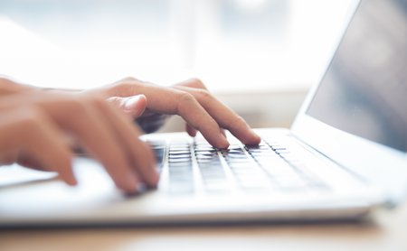 Nahaufnahme von einer Person, die an einem Laptop arbeitet