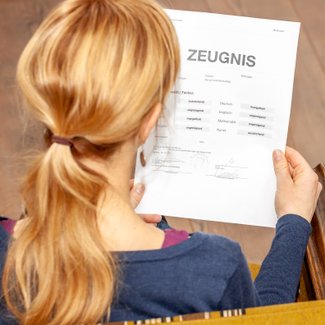 Eine Frau hält ein schlechtes Schulzeugnis in der Hand.