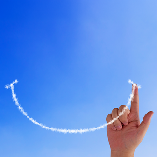 Hand malt einen Smiley in den Himmel