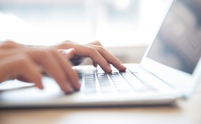 Nahaufnahme von einer Person, die an einem Laptop arbeitet