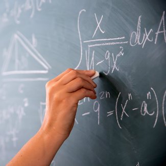 Nahaufnahme einer Hand, die auf einer Tafel rechnet.