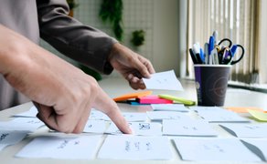 Bild von Händen, die Notizblätter sortieren